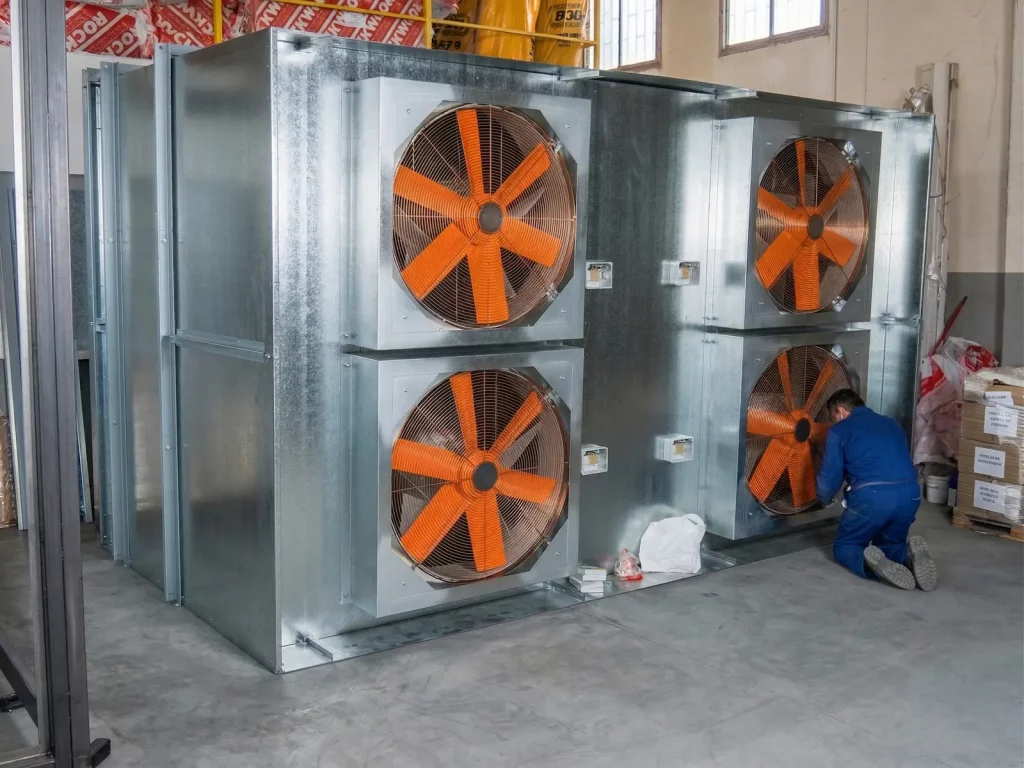 4 ventiladores industriales en una instalación de fabrica industrial conectado a silenciadores acústicos para conseguir reducción acústica y ventilación insonorizada.